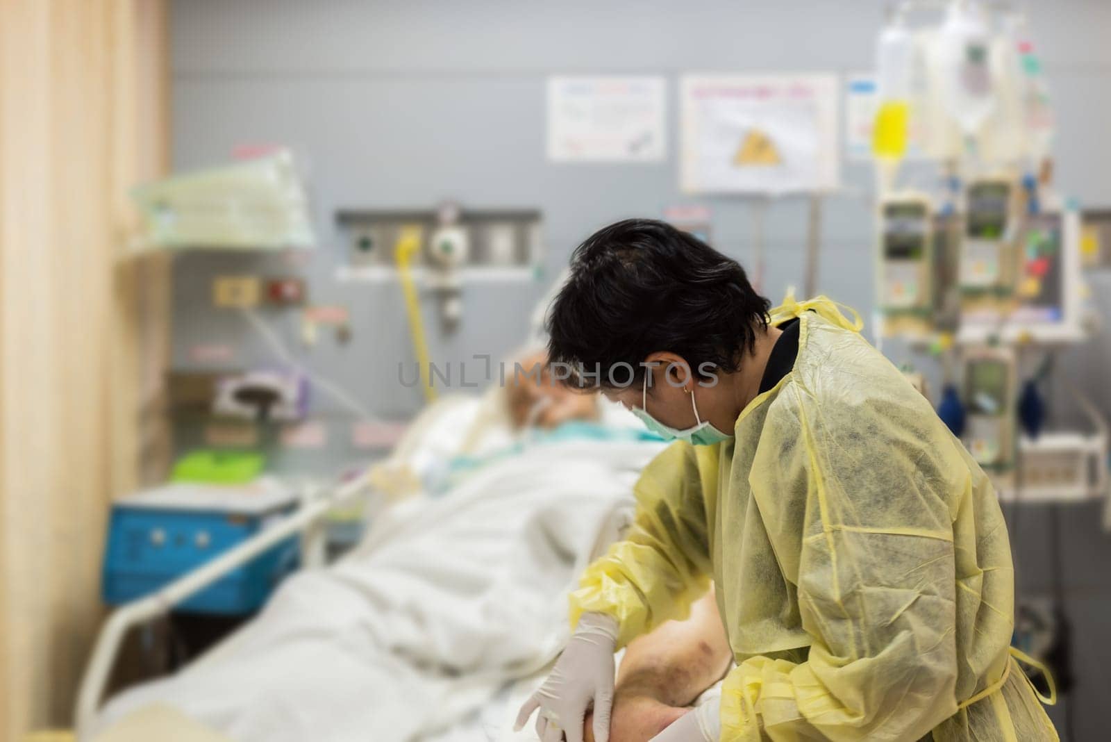 Asian women 40s years old is a patient relative taking care of the CRE. or VRE. infected elder patient 80s years old on patient bed in intensive care unit (ICU.) room at hospital.