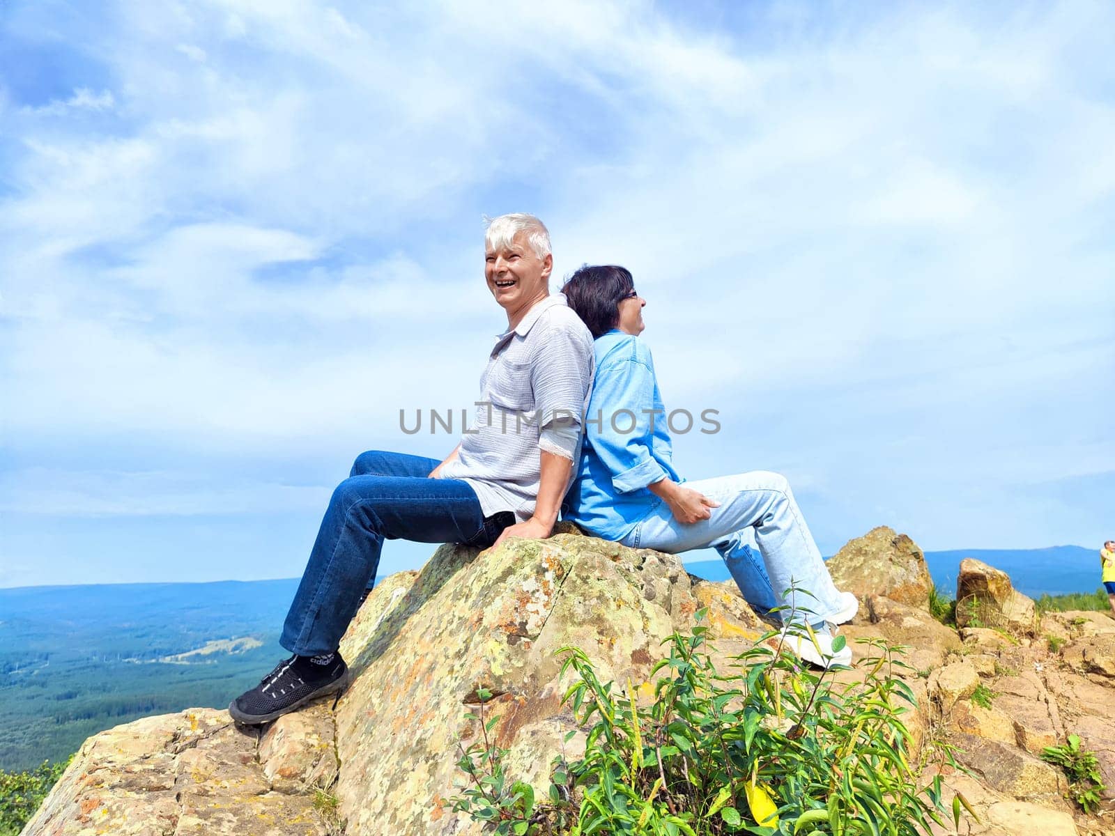 Friends relax together on a large rock, sharing laughter and peaceful views of the expansive valley below them.