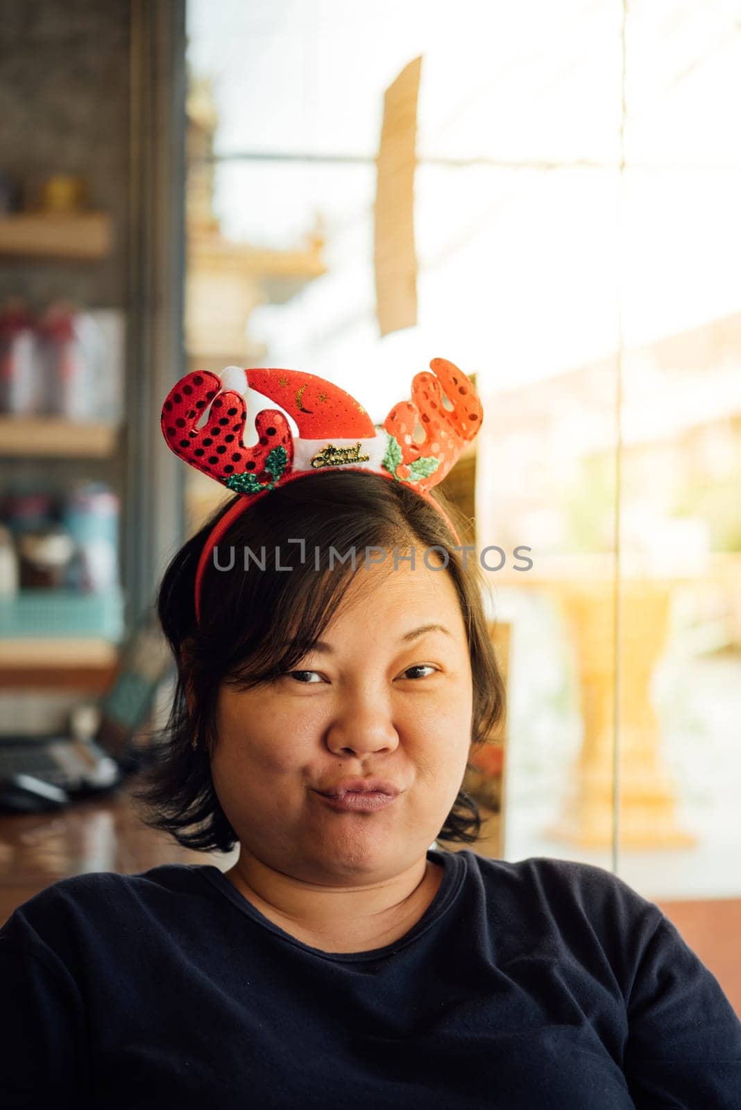 Asian woman 40s white skin have a laughing smile gesture in a coffee shop cafe with santa claus headband in merry christmas and new year celebration