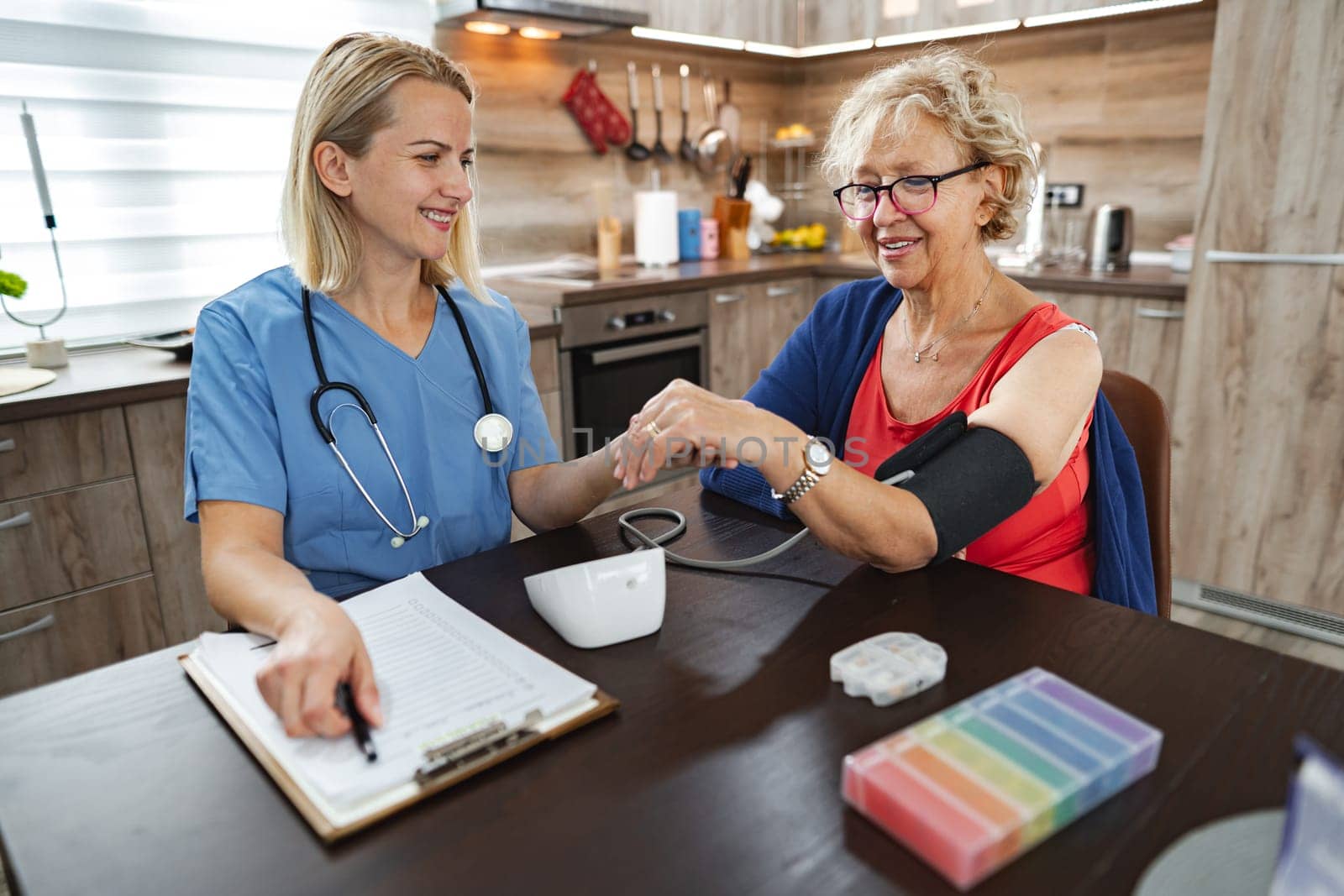 A friendly nurse takes blood pressure while chatting with a smiling patient.