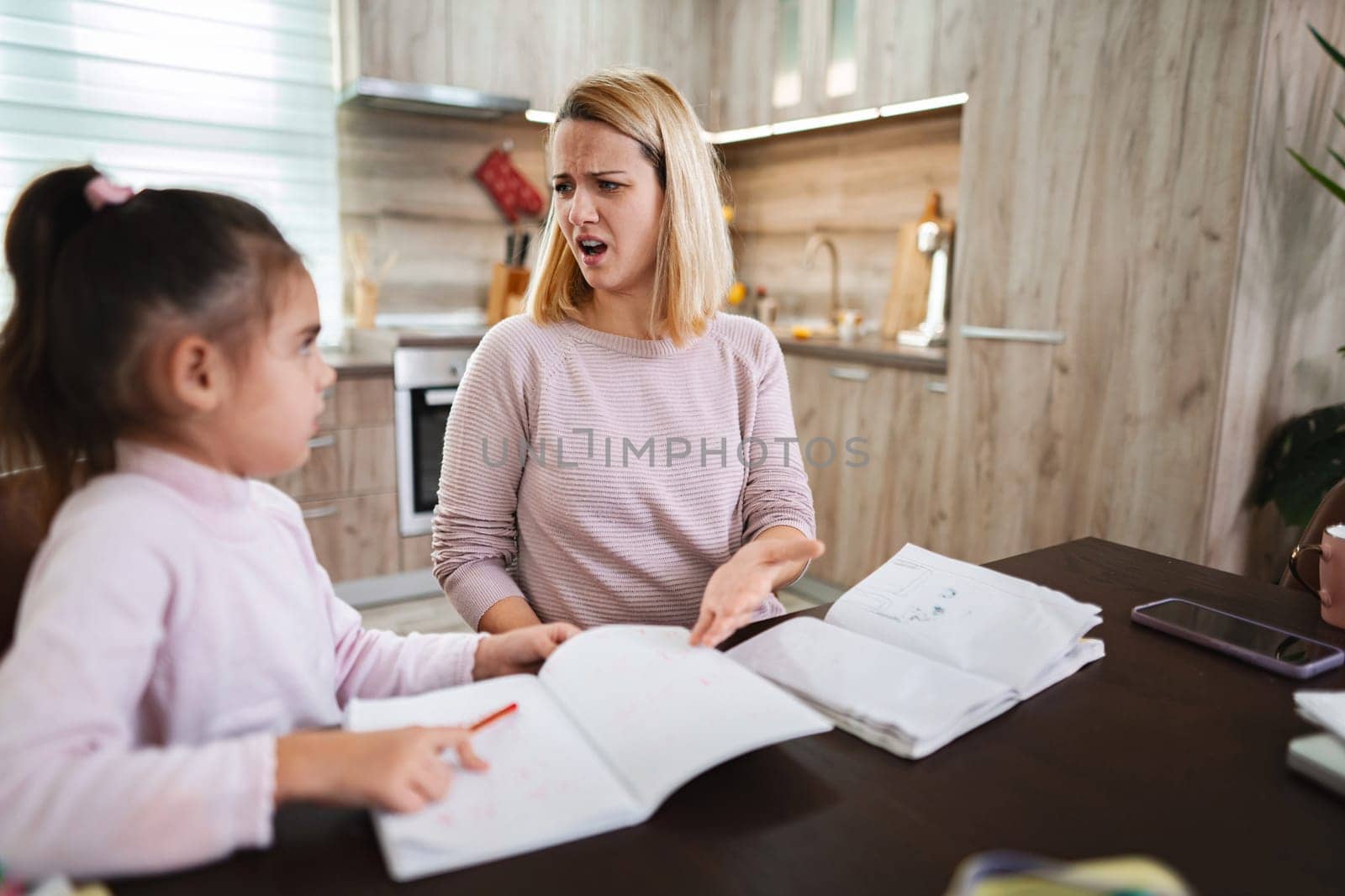 Frustrated mother guides her daughter through assignments at home.