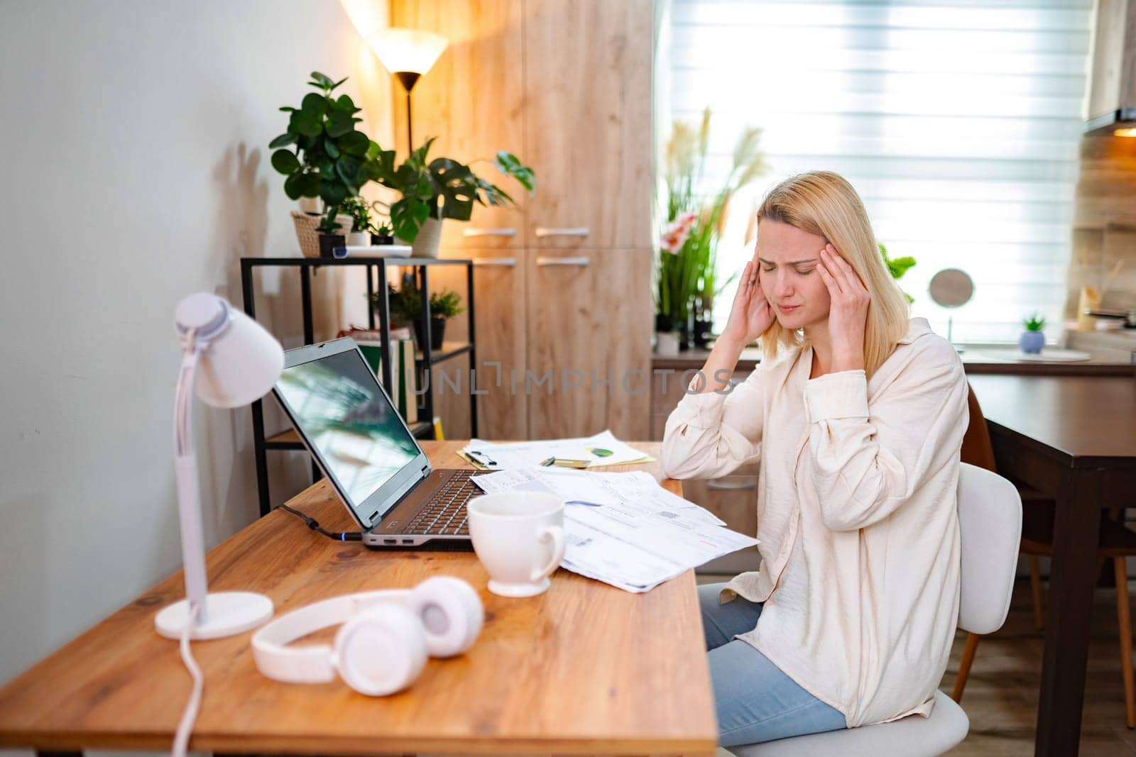 A young woman looks stressed while tackling her tasks in a home office.