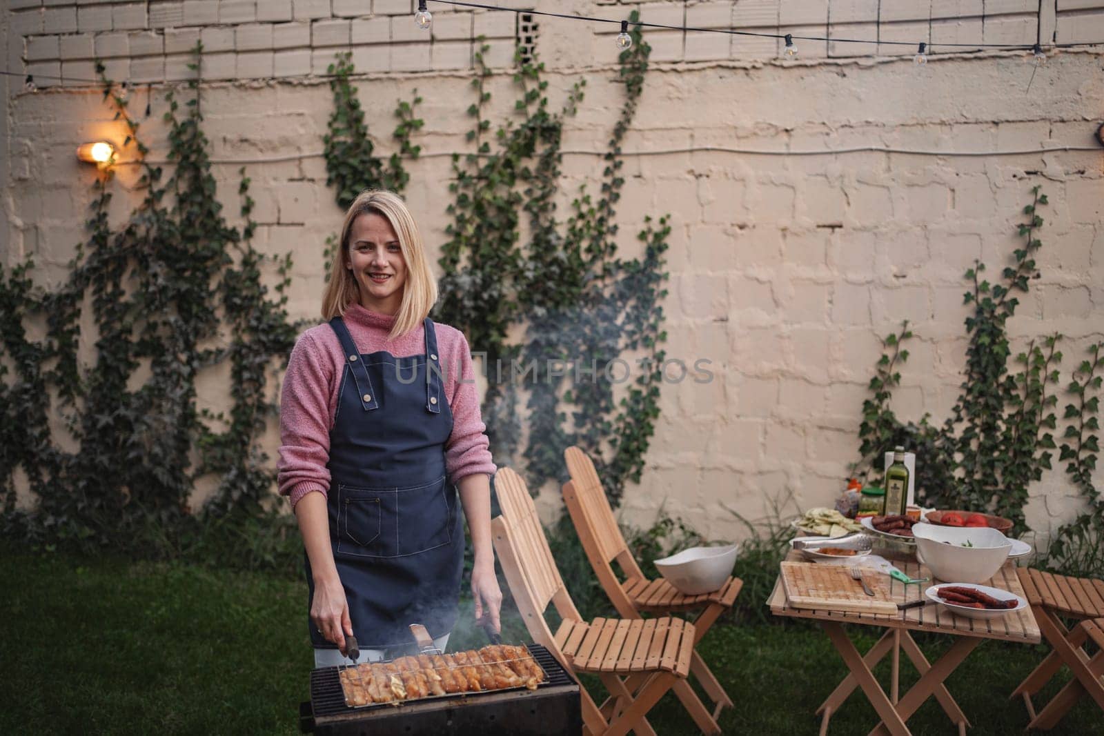 A woman grills delicious food in a cozy backyard, surrounded by nature.