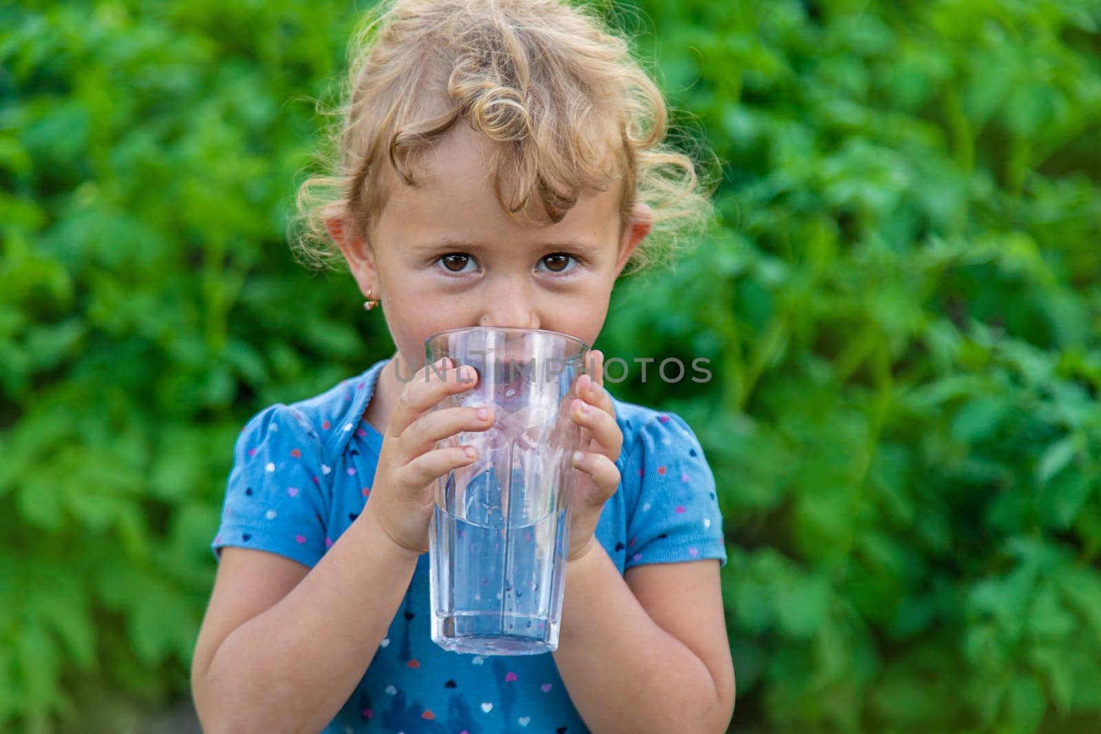 A child drinks water from a glass. Selective focus. Kid.