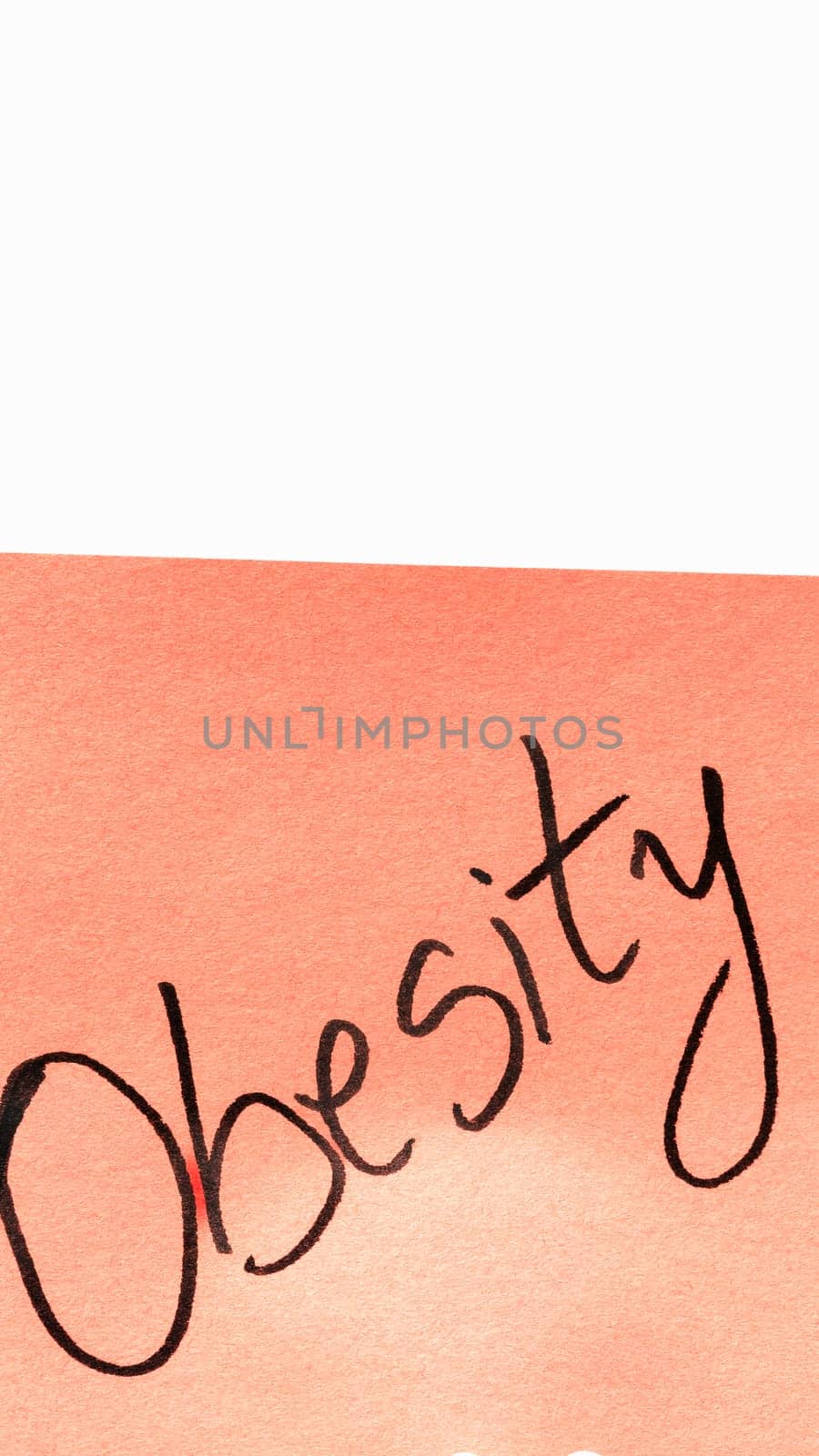Obesity handwriting text close up isolated on orange paper with copy space. Writing text on memo post reminder
