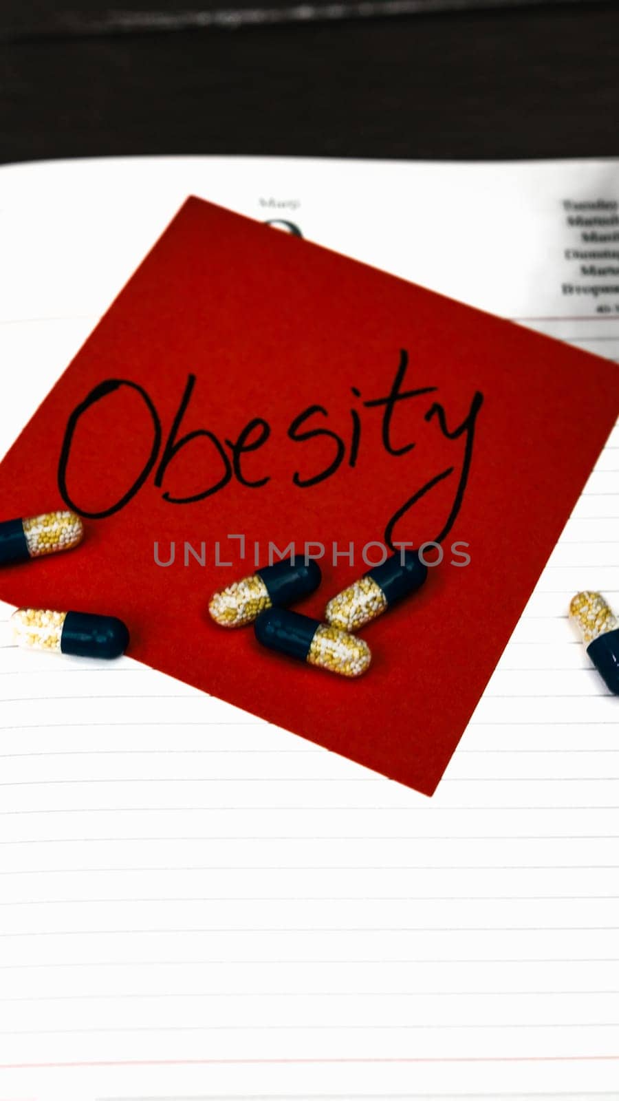 Writing Obesity memo post reminder and medicines, pills.  Writing  Obesity on sticky paper.