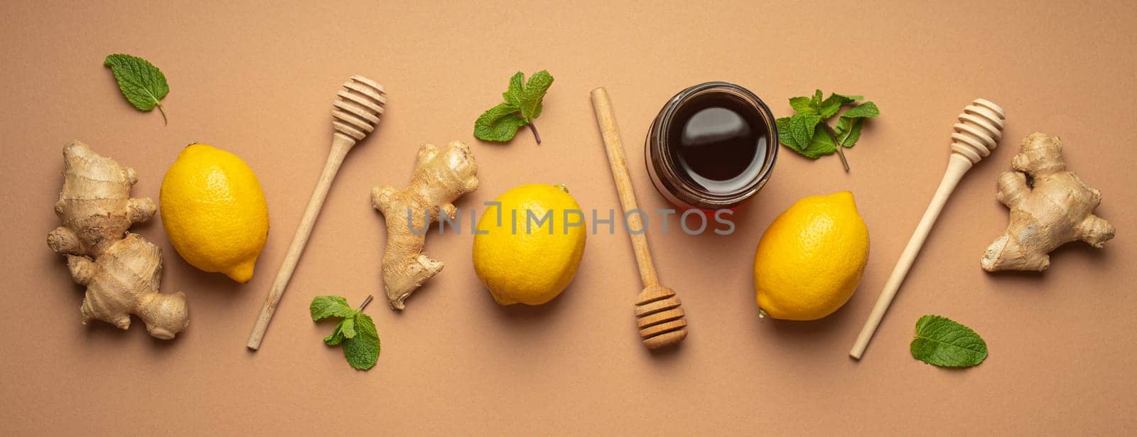 Composition with lemons, mint, ginger, honey in glass jar and honey wooden dippers top view. Food for immunity stimulation and against seasonal flu. Healthy natural remedies to boost immune system.