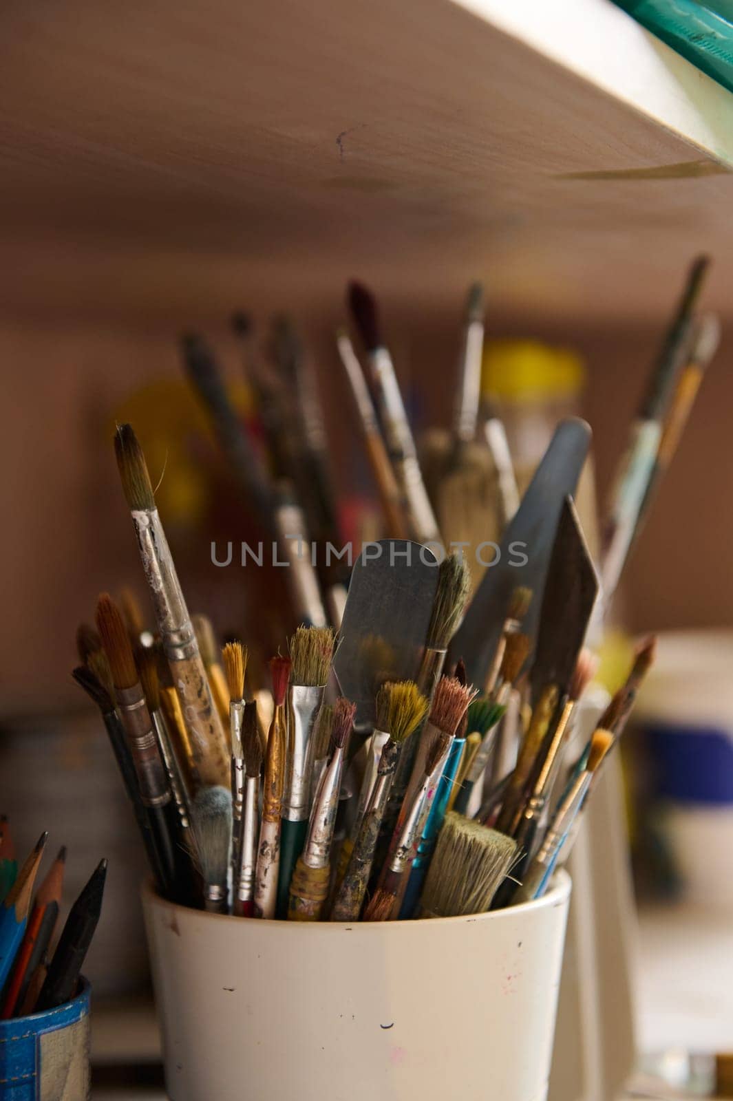 Still life with oil paintbrushes near canvas in workshop. Fine art. Visual art. Creative hobby and occupation. Painting and drawing tools. Vertical photography for advertisement