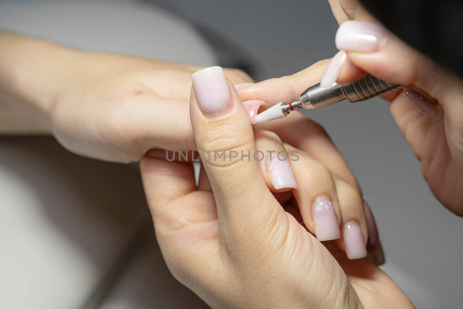 Female hands and tools for manicure, process of performing manicure in beauty salon. Nail care procedure in a beauty salon. Gloved hands of a skilled manicurist cutting cuticles. Concept spa body care