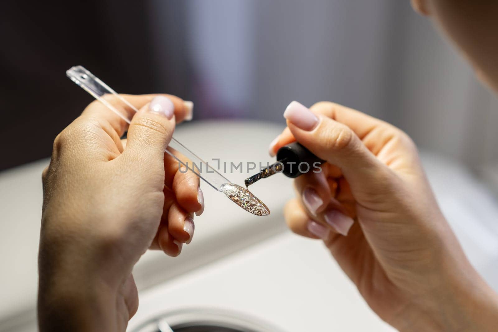 A manicurist applies gel nail polish to empty tips as a sample by AnatoliiFoto