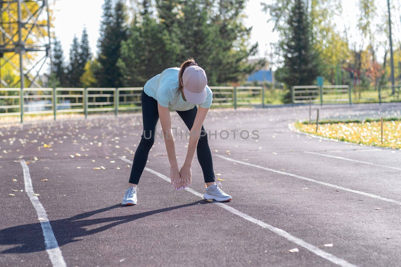 A young beautiful woman in sportswear plays sports at a local stadium. Exercise, jog and exercise at the beginning of the day. Healthy and active lifestyle.