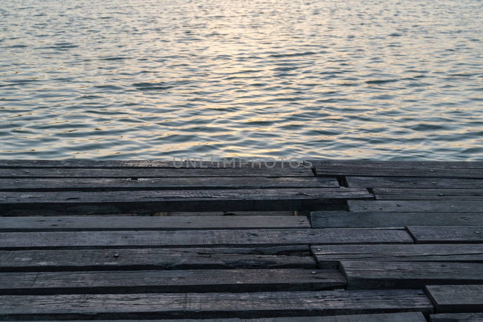 Sunlight in sunset time reflection on water wave in lake with wood floor