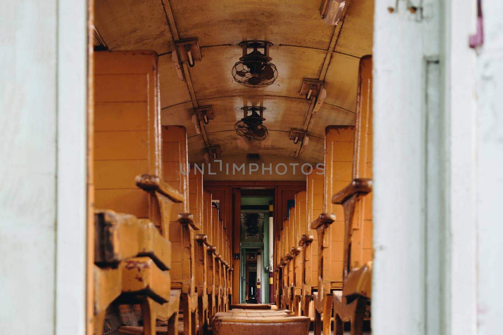 Inside of old public Thai railway train cabin with seats, handrails, fan and interior in vintage style service for passenger transport
