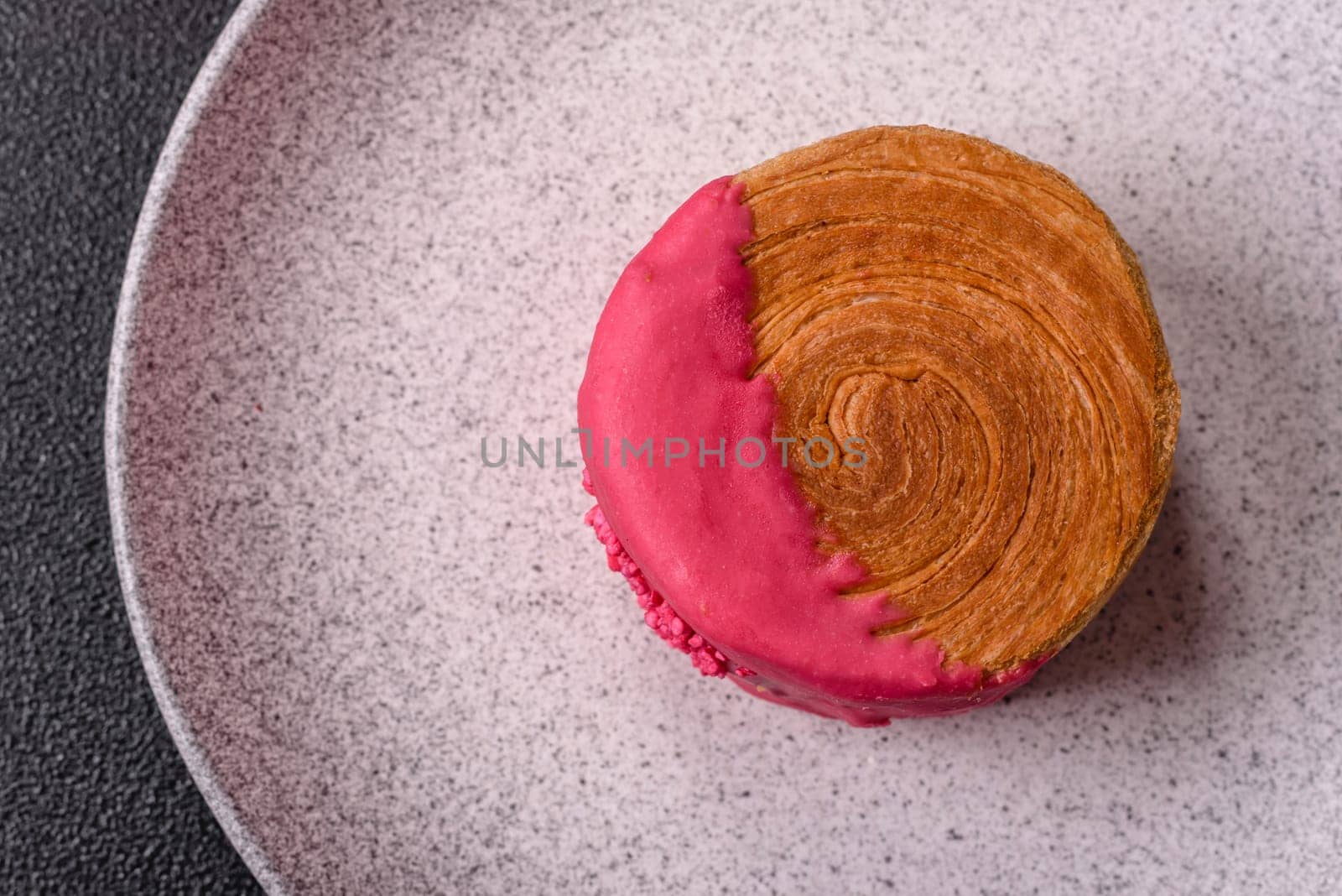 Round sweet New York roll croissant with raspberry cream filling on a dark concrete background