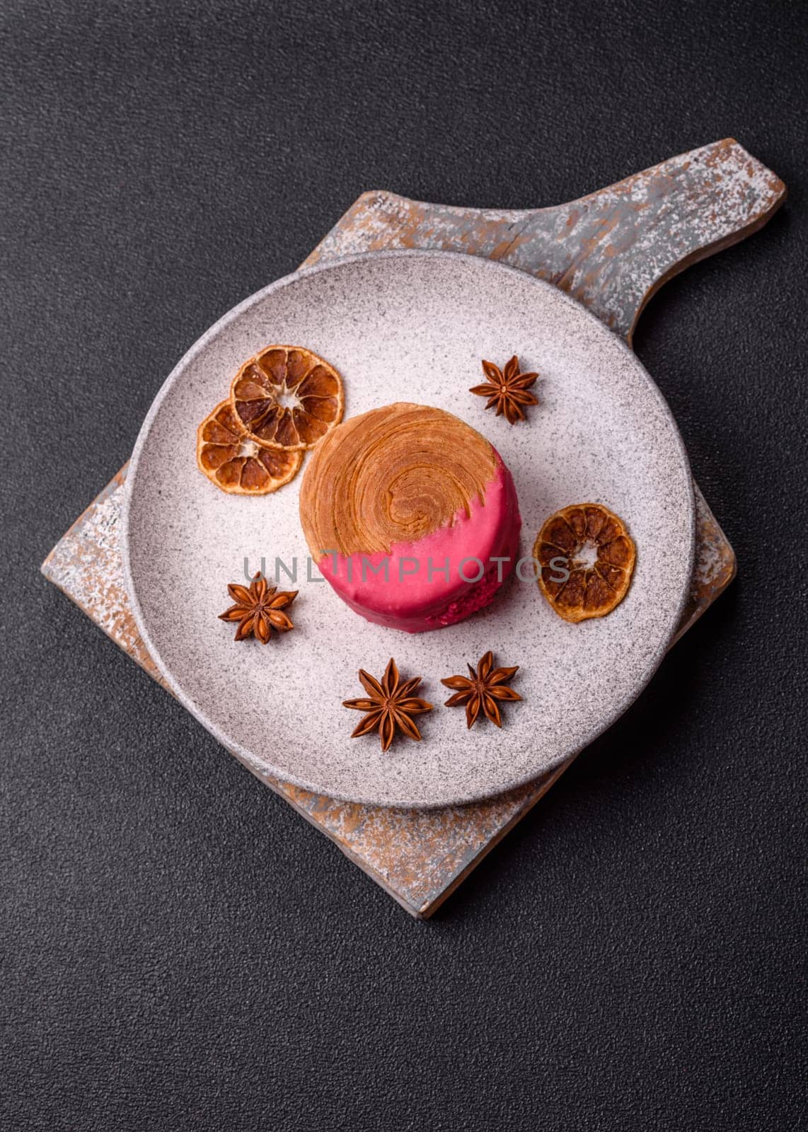 Round sweet New York roll croissant with raspberry cream filling on a dark concrete background