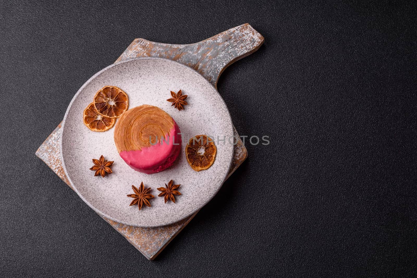 Round sweet New York roll croissant with raspberry cream filling on a dark concrete background