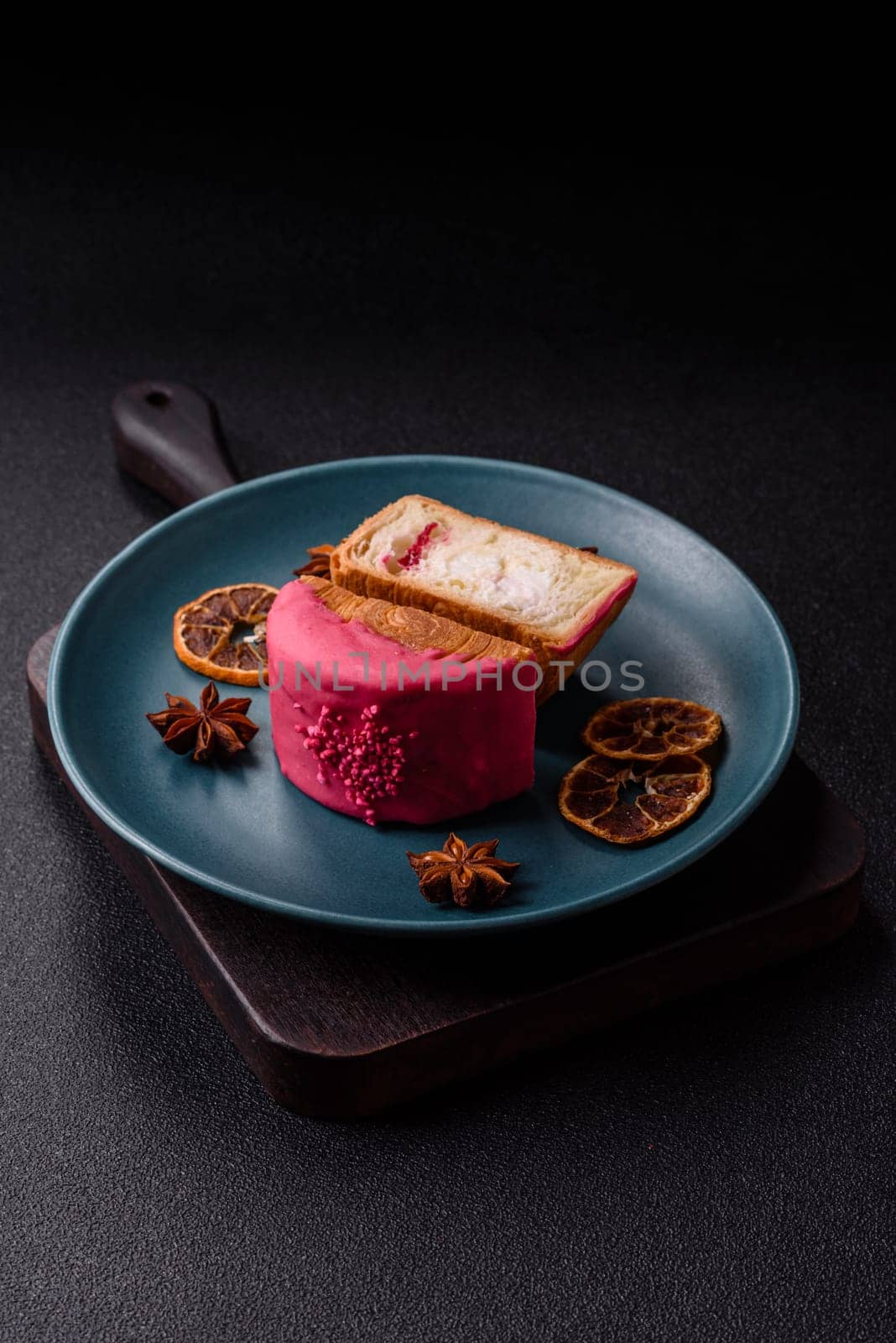 Round sweet New York roll croissant with raspberry cream filling on a dark concrete background