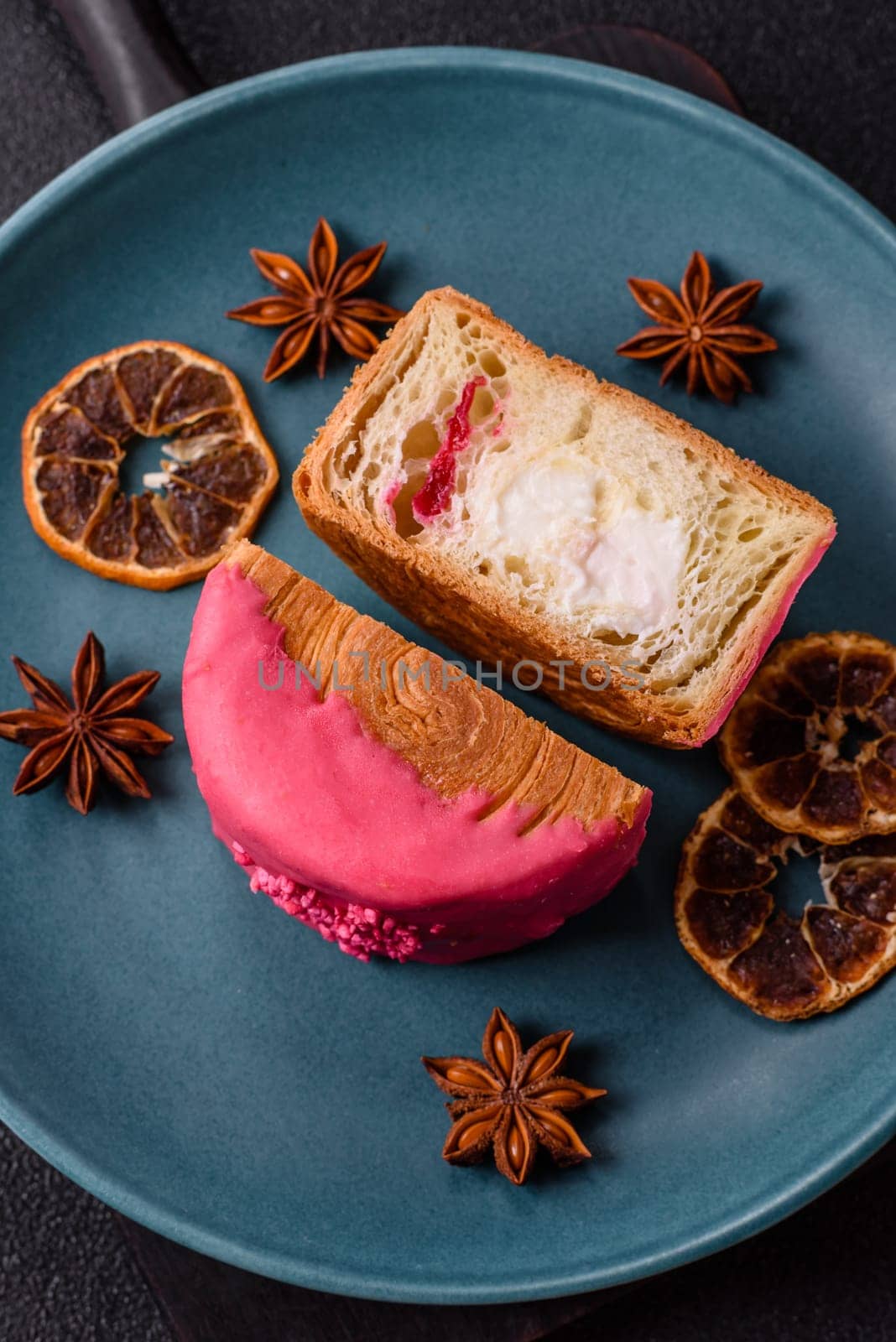 Round sweet New York roll croissant with raspberry cream filling on a dark concrete background