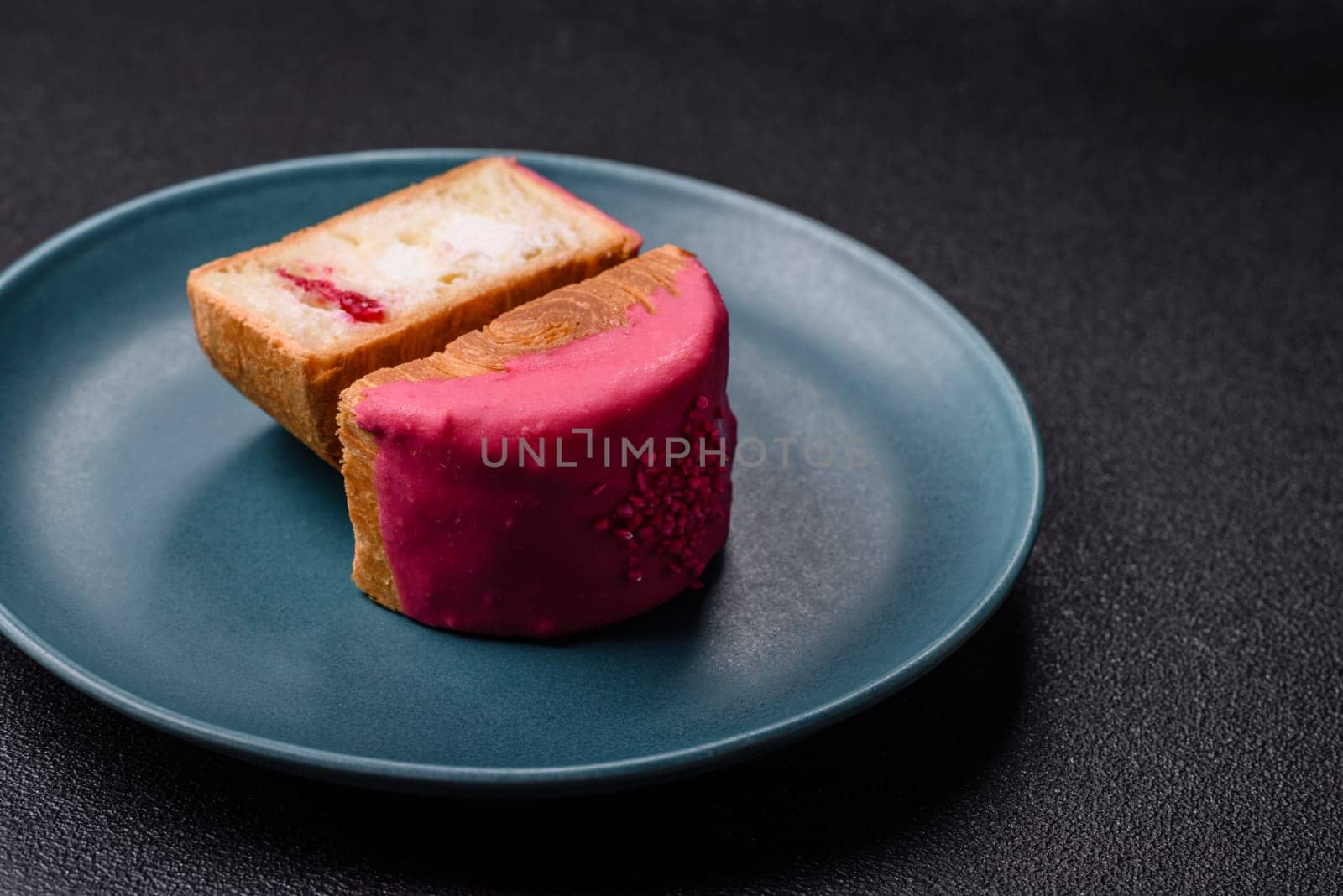 Round sweet New York roll croissant with raspberry cream filling on a dark concrete background