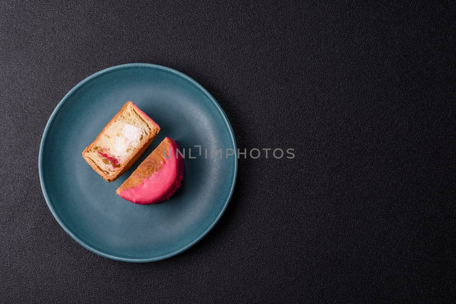 Round sweet New York roll croissant with raspberry cream filling on a dark concrete background