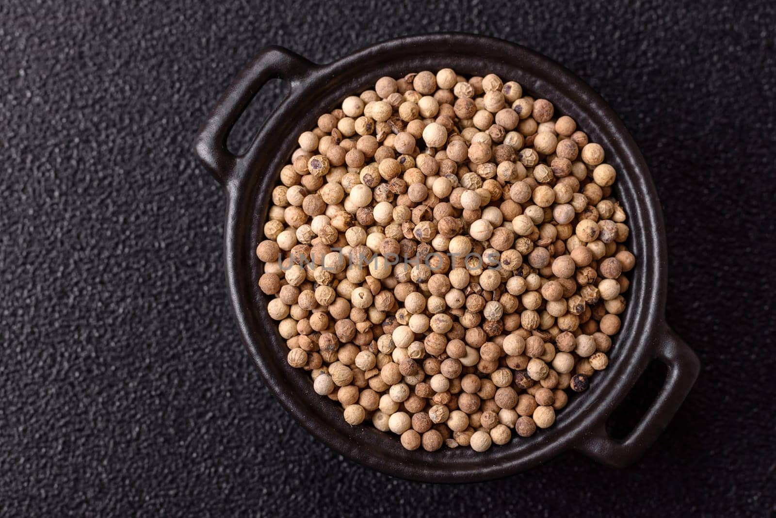 White allspice in a ceramic bowl on a dark concrete background