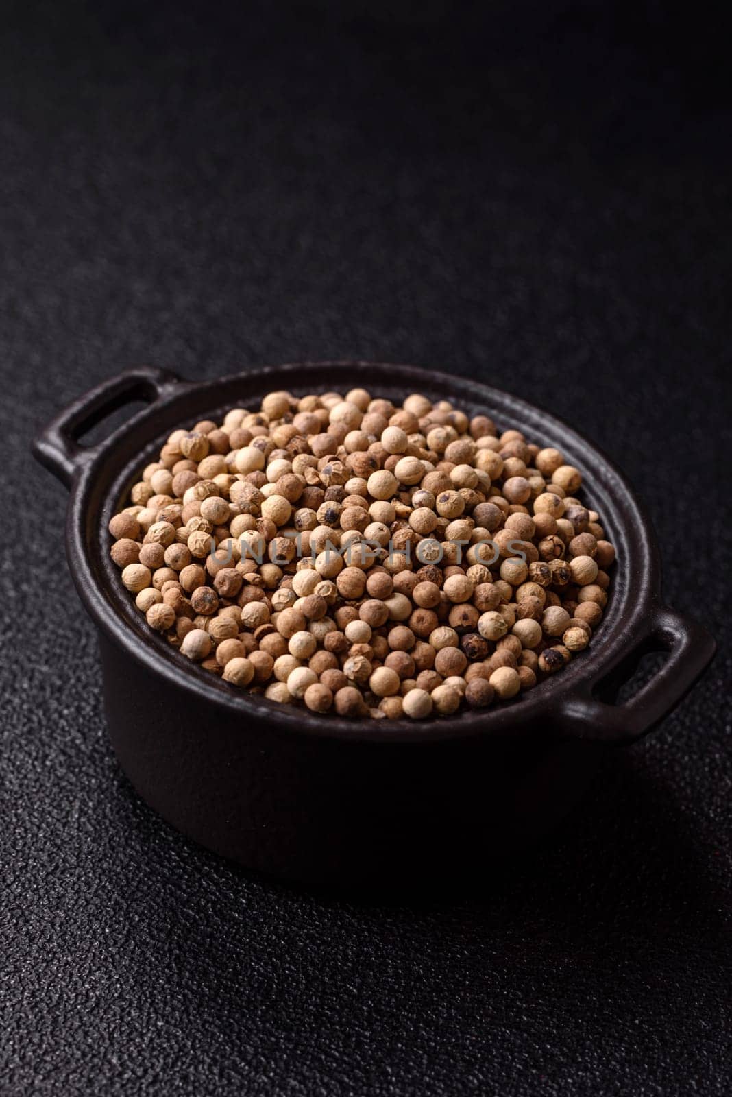 White allspice in a ceramic bowl on a dark concrete background