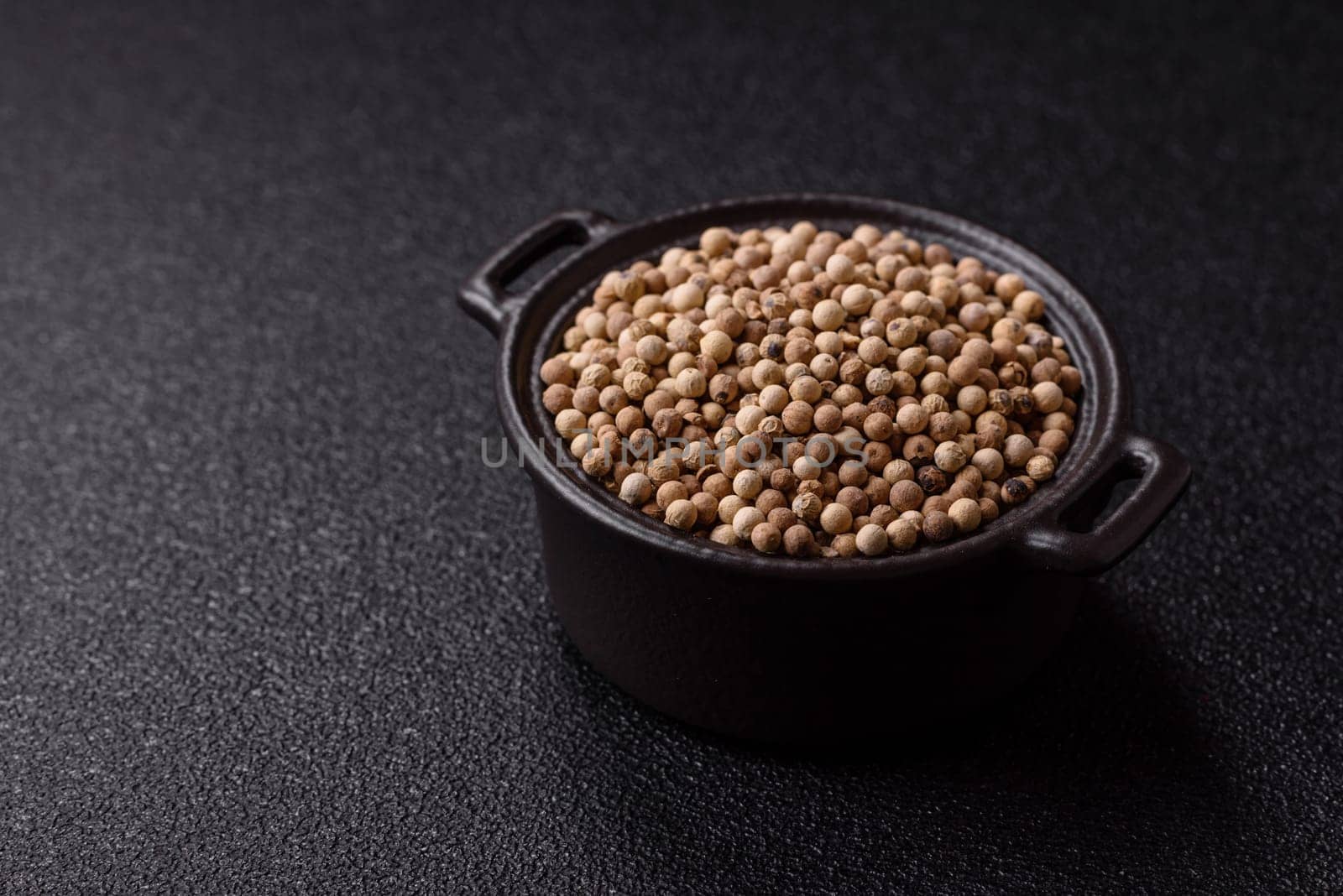 White allspice in a ceramic bowl on a dark concrete background