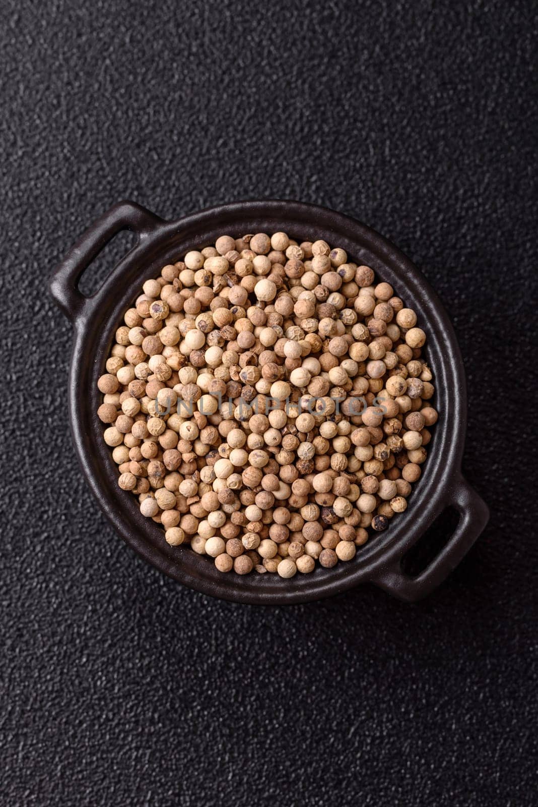 White allspice in a ceramic bowl on a dark concrete background