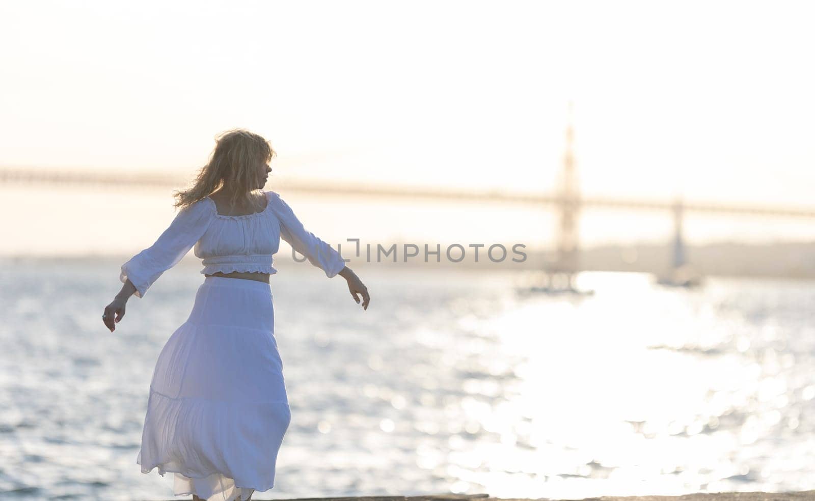 Young woman is happily dancing on the pier at sunset with the golden gate bridge in the background