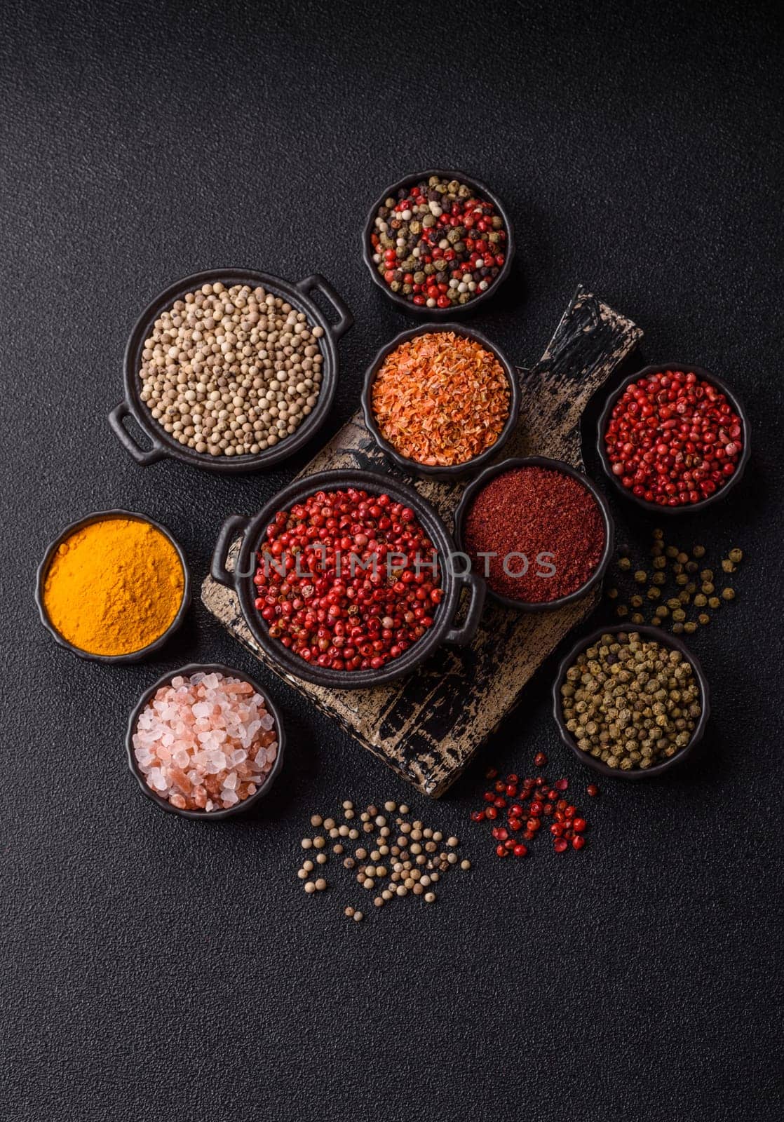 Variations of spices, allspice, turmeric, paprika, salt in ceramic bowls on a dark concrete background