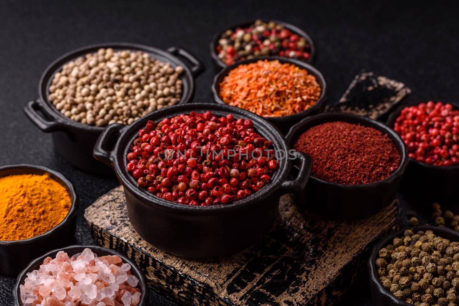 Variations of spices, allspice, turmeric, paprika, salt in ceramic bowls on a dark concrete background