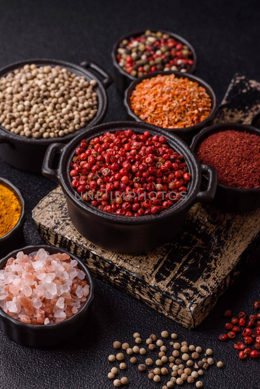 Variations of spices, allspice, turmeric, paprika, salt in ceramic bowls on a dark concrete background
