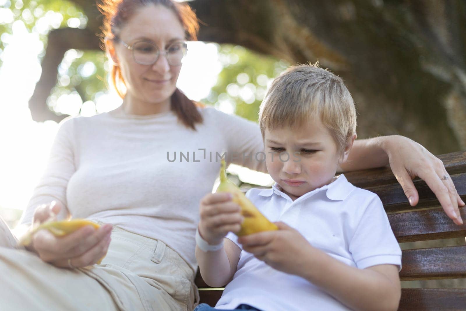 Young boy looking sad while holding a banana and having a difficult conversation with his mother