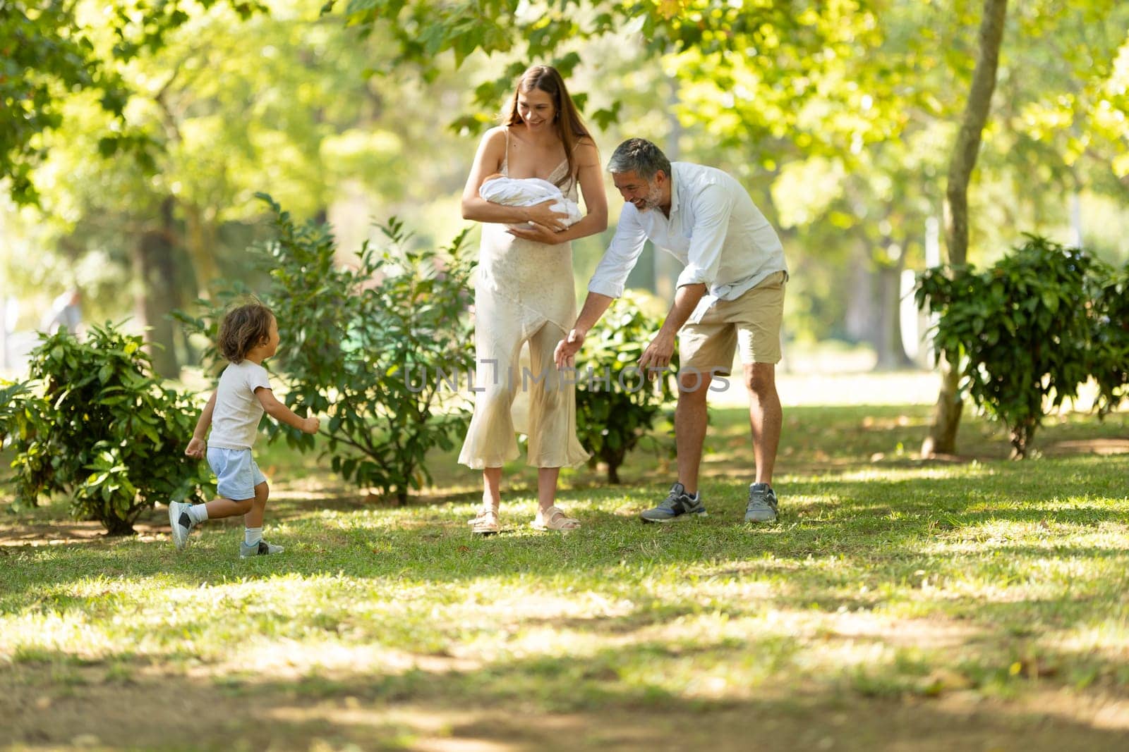 Young family is enjoying a walk together in the park on a sunny summer day