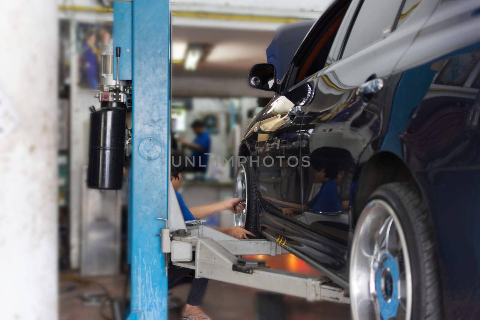 Serviceman checking suspension in a car at garage