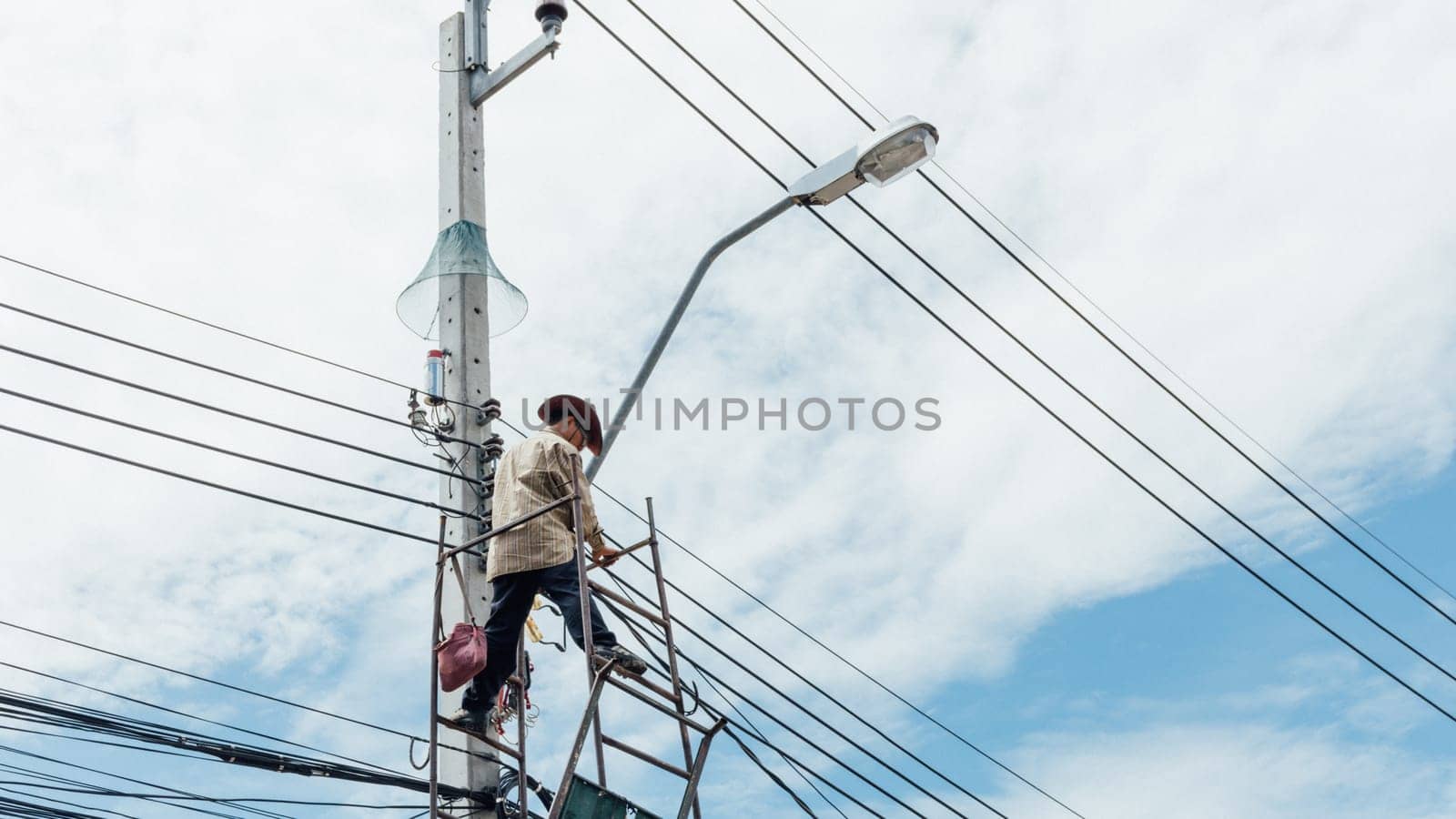 Worker working to install electric line by scaffolding on pickup truck at Bangkok Thailand.