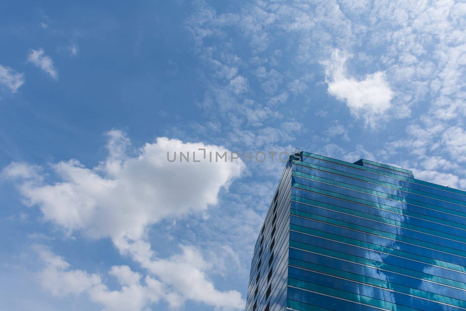 Big glass office building with blue sky and white cloud
