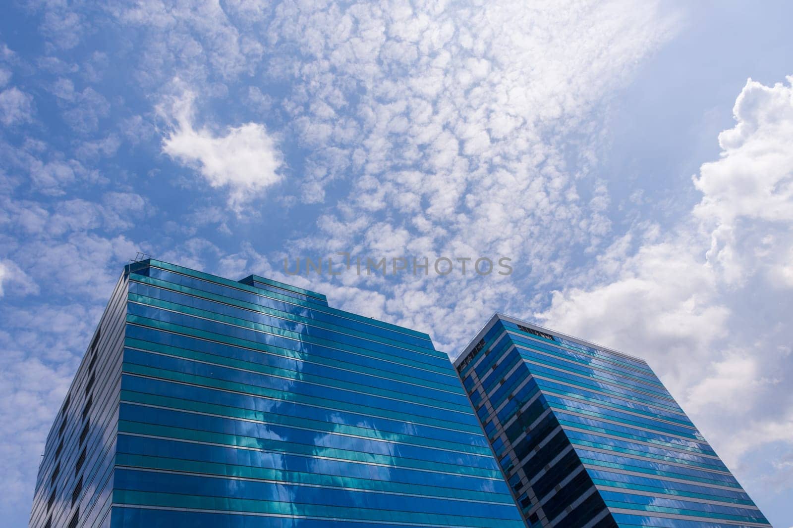 Big glass office building with blue sky and white cloud