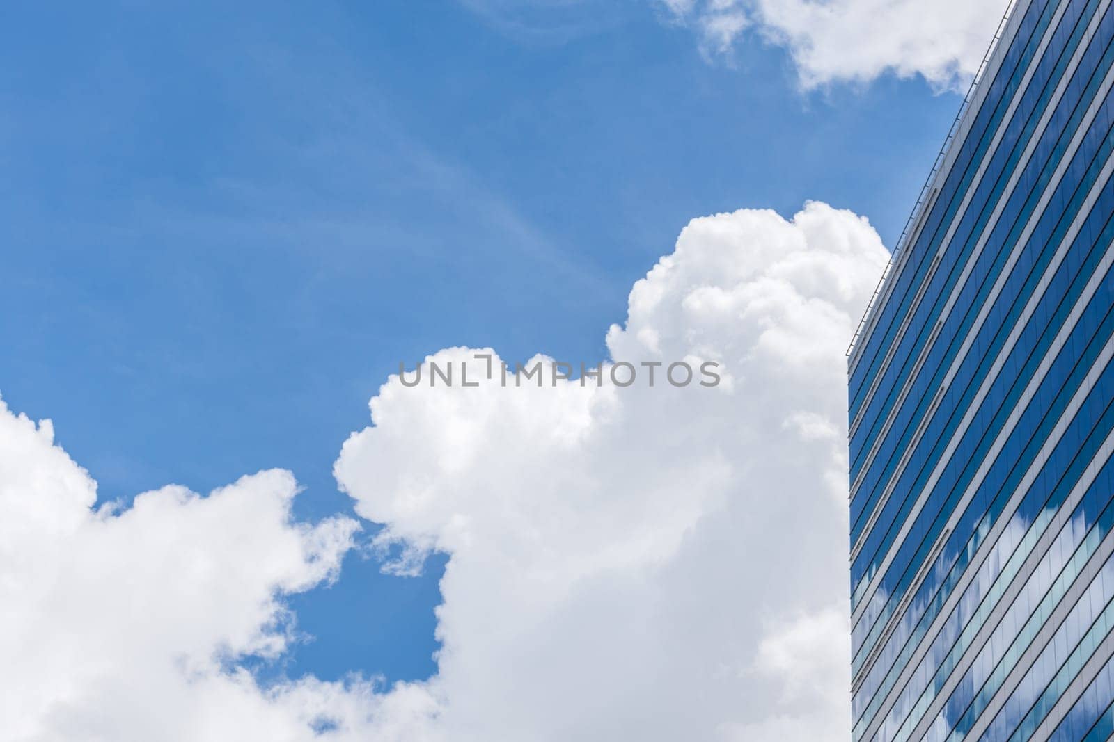 Exterior of glass office building reflection with blue sky and white cloud in a city with business, finance, construction and global warming concept