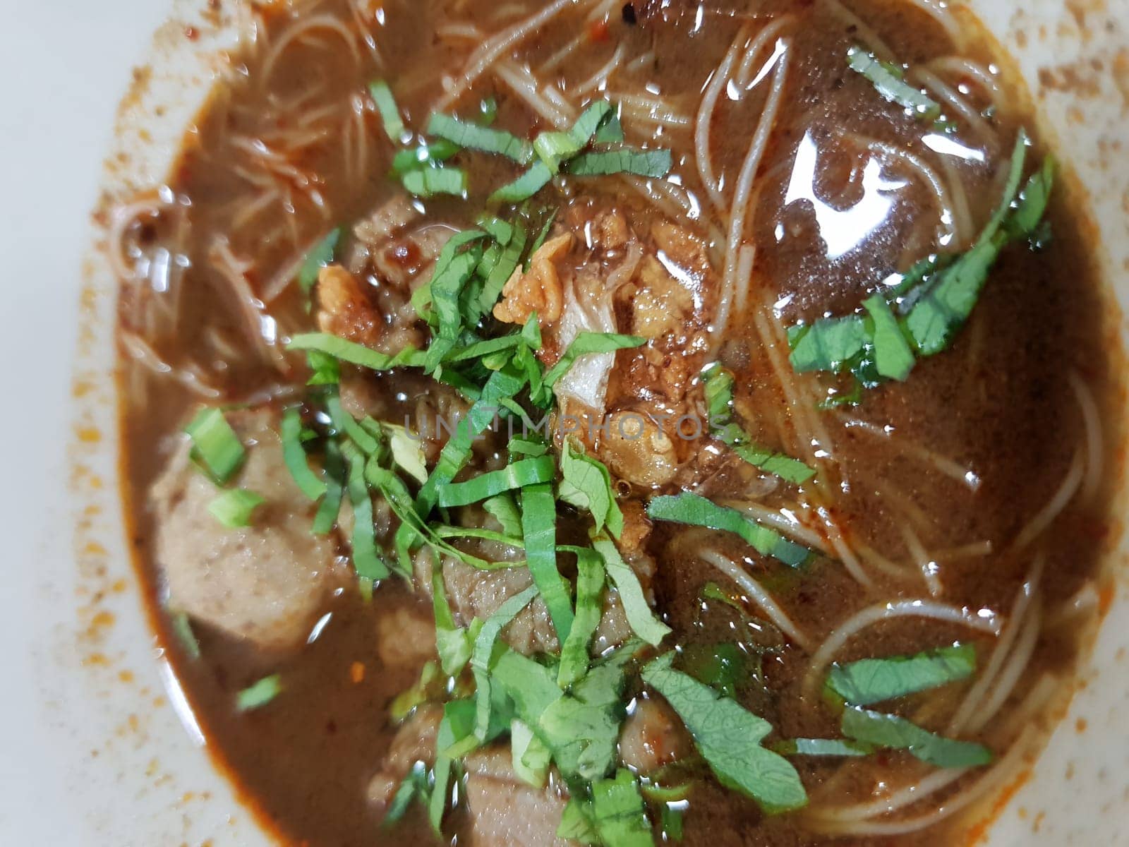 Braised beef clear noodle with meat balls soup stew (Ekaehla meat) with vegetable in bowl for sale at Thai street food market or restaurant in Thailand