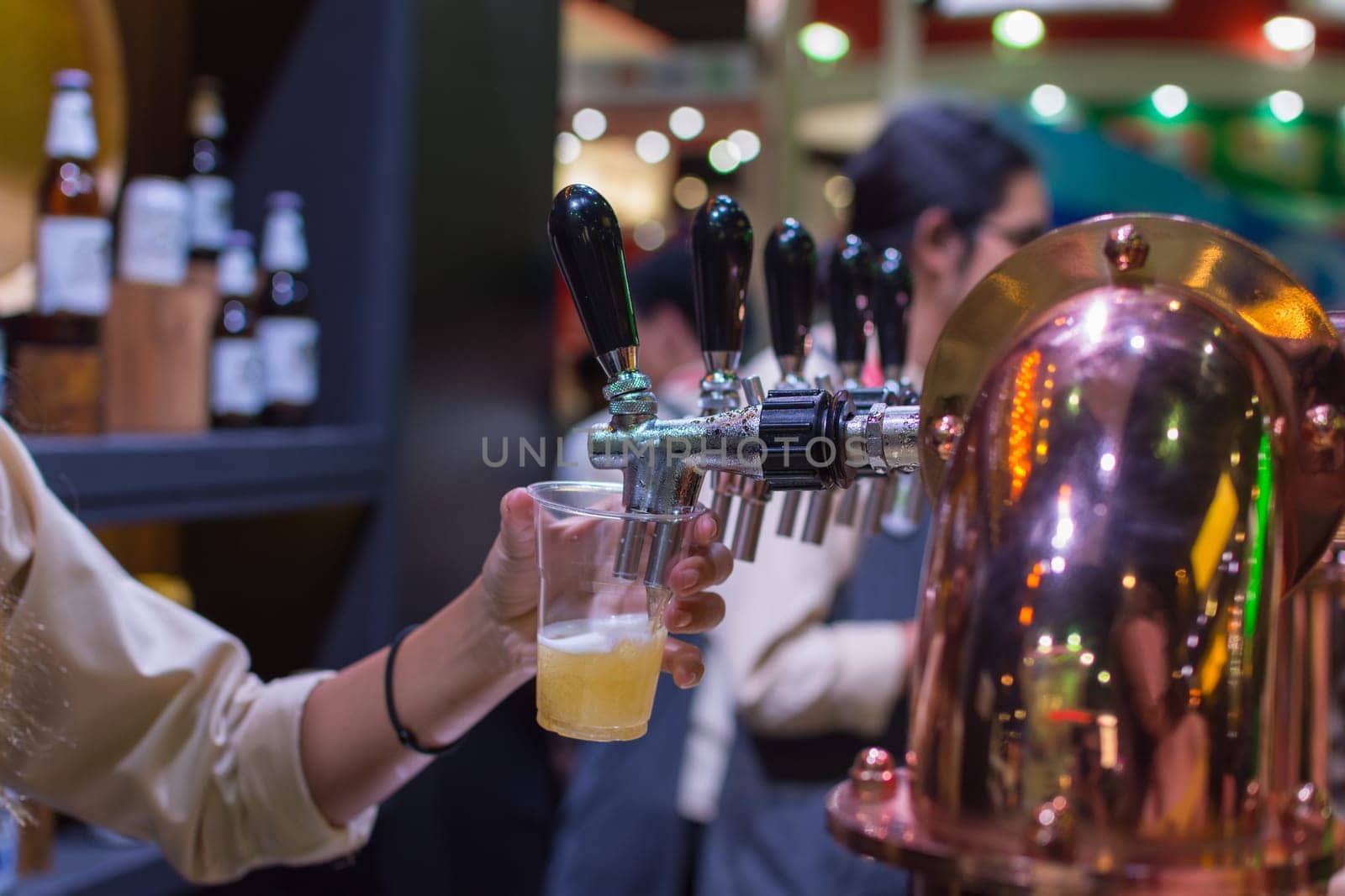 Barman or bartender pouring a draught lager beer from beer tap on counter for serving in a restaurant or pub.