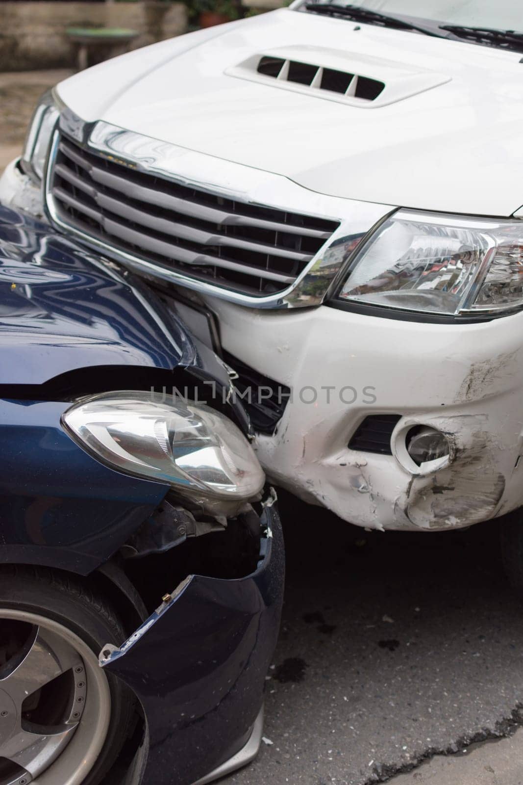 Car crash from car accident on the road in a city between saloon versus pickup wait insurance.