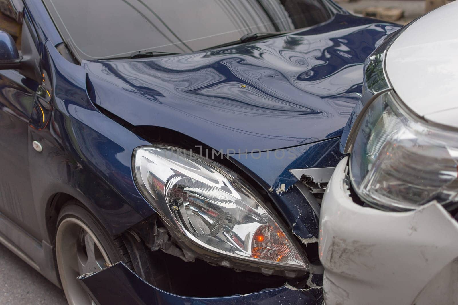 Car crash from car accident on the road in a city between saloon versus pickup wait insurance.