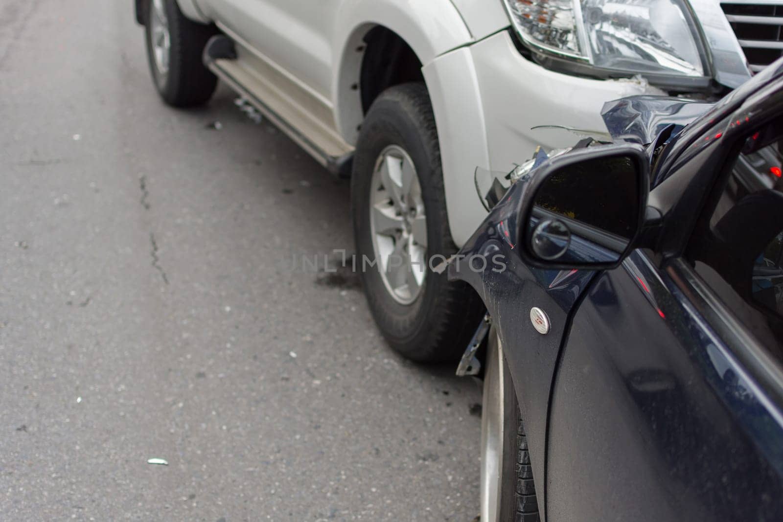 Car crash from car accident on the road in a city between saloon versus pickup wait insurance.