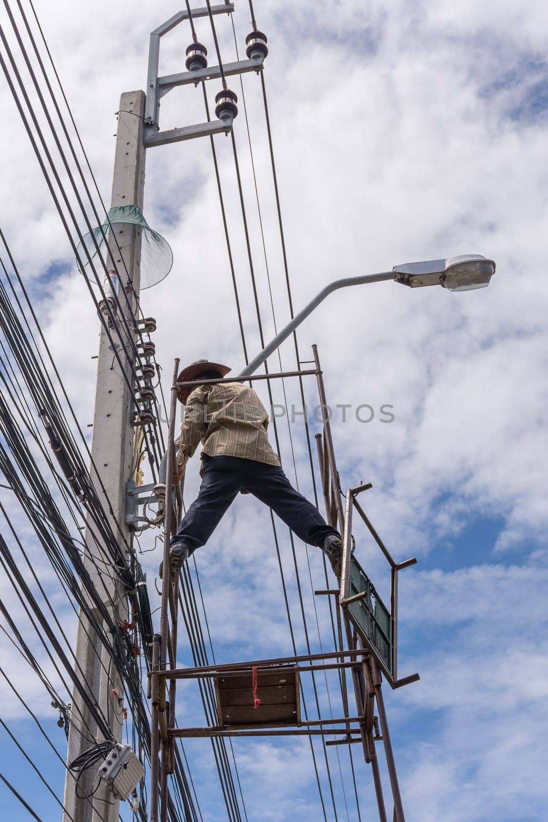 Worker working to install electric line by scaffolding on pickup truck at Bangkok Thailand.