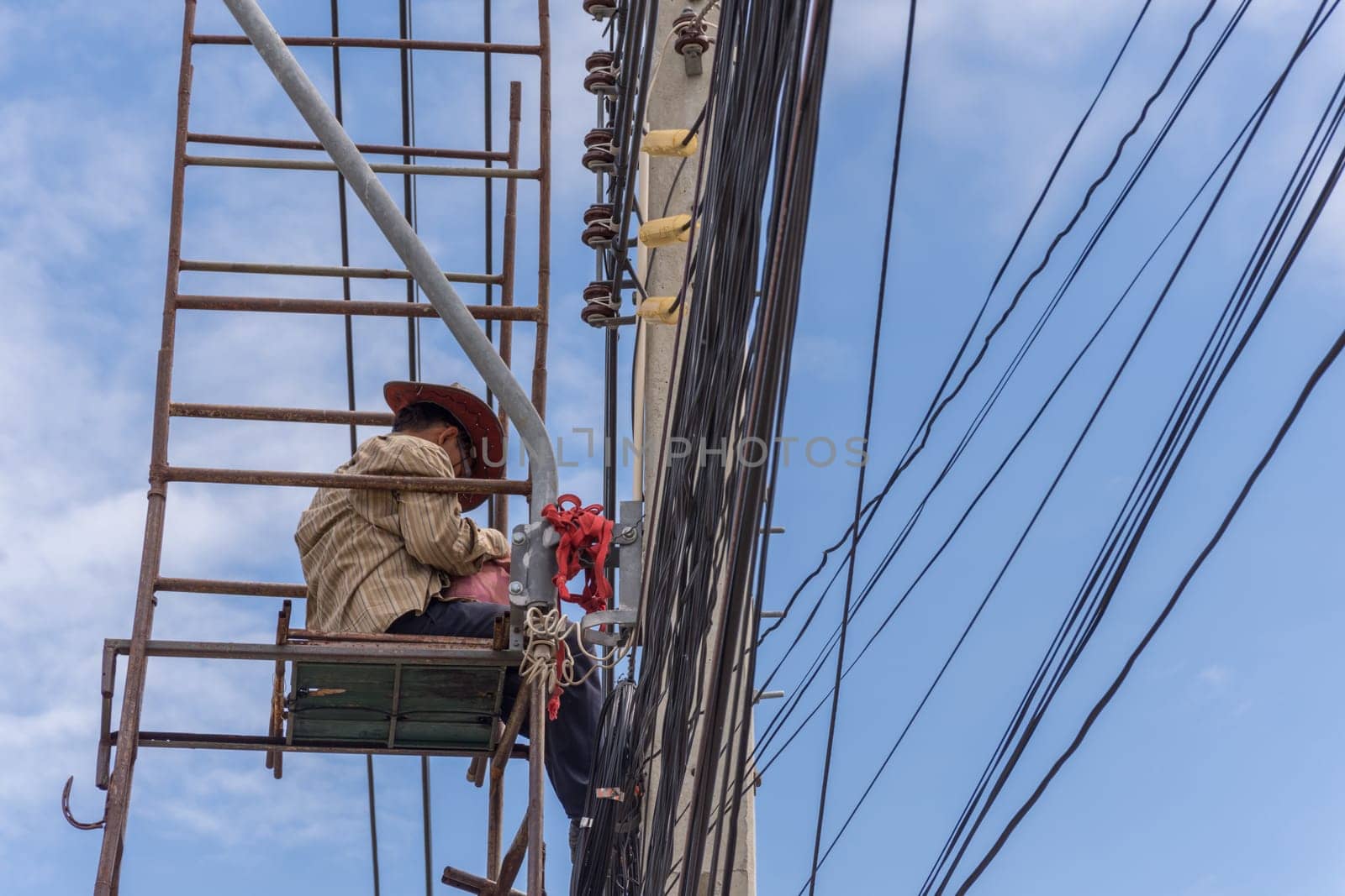 Worker working to install electric line by scaffolding on pickup truck