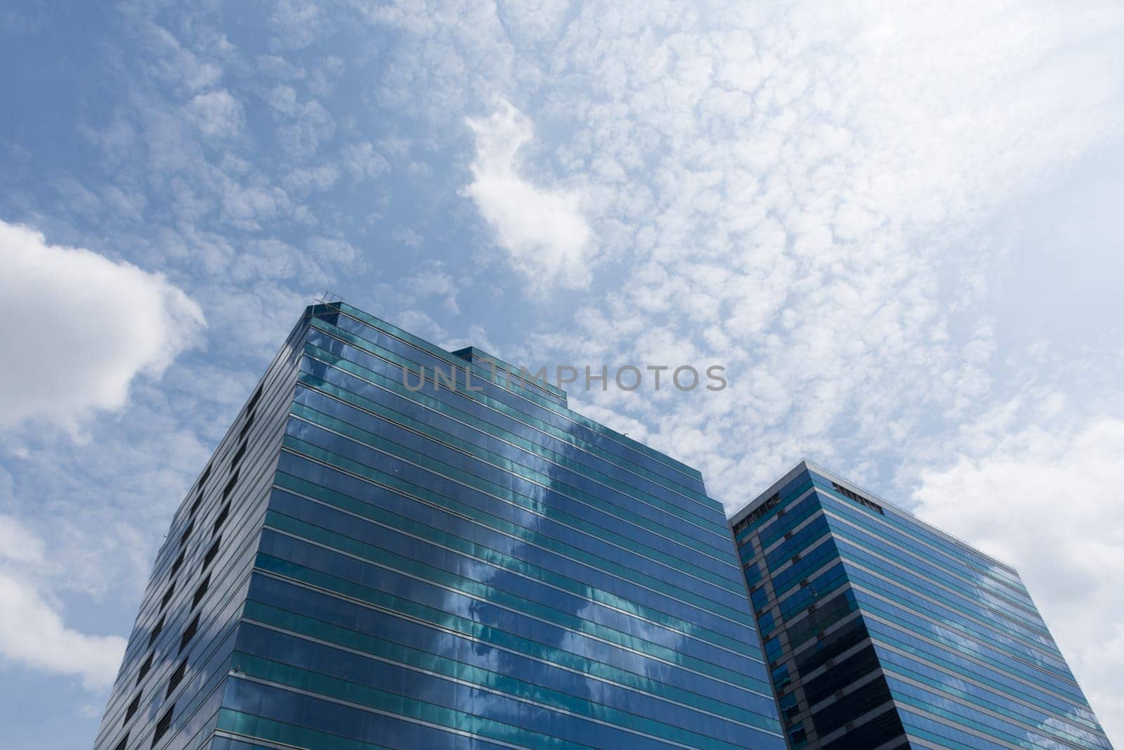 Big glass office building with blue sky and white cloud