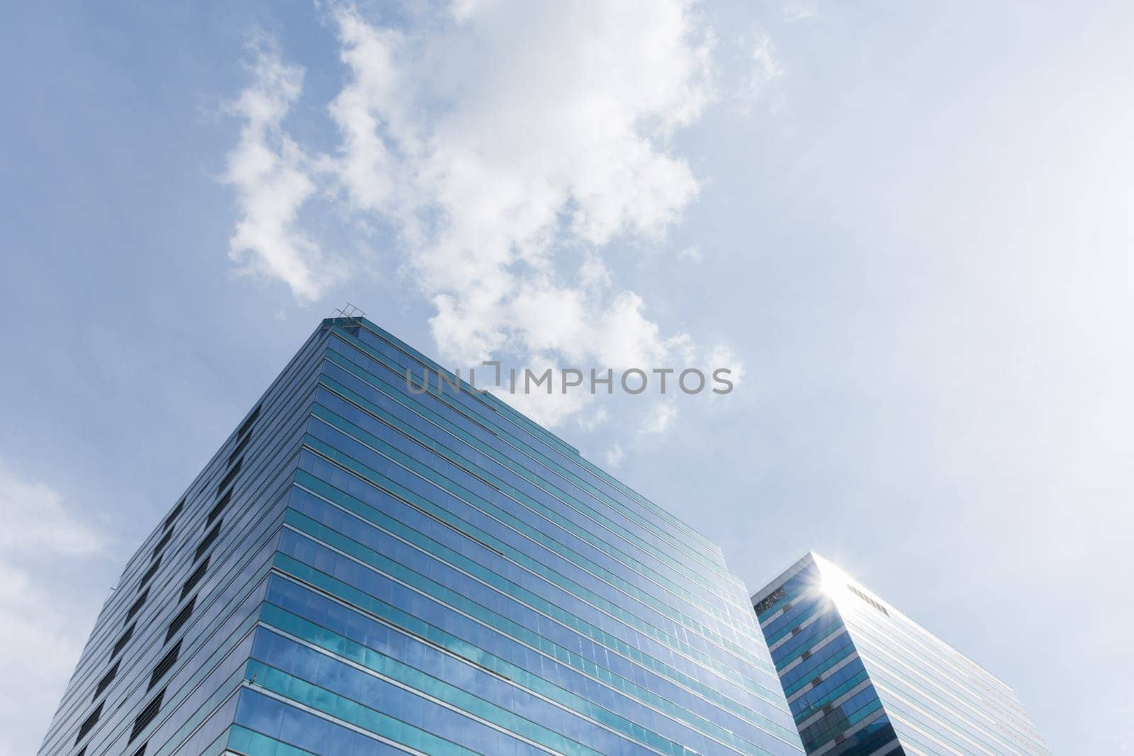 Big glass office building with blue sky and white cloud