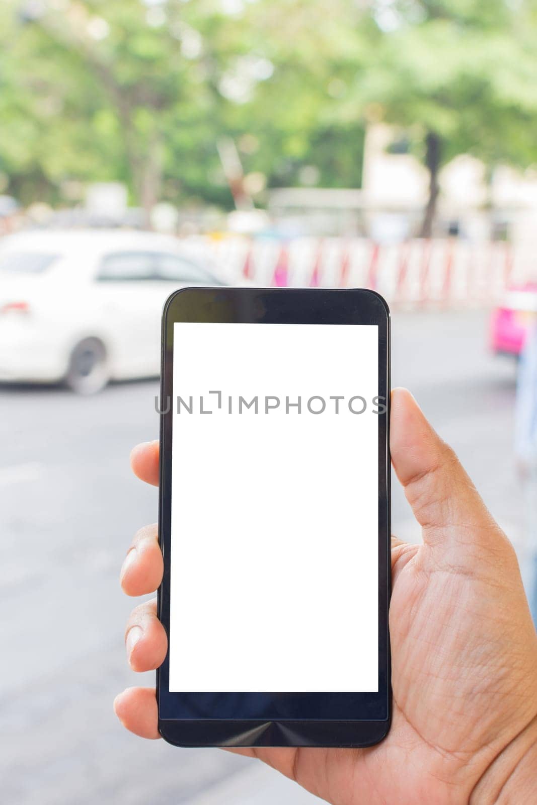 Person hand holding smartphone or mobile phone with white screen using on road