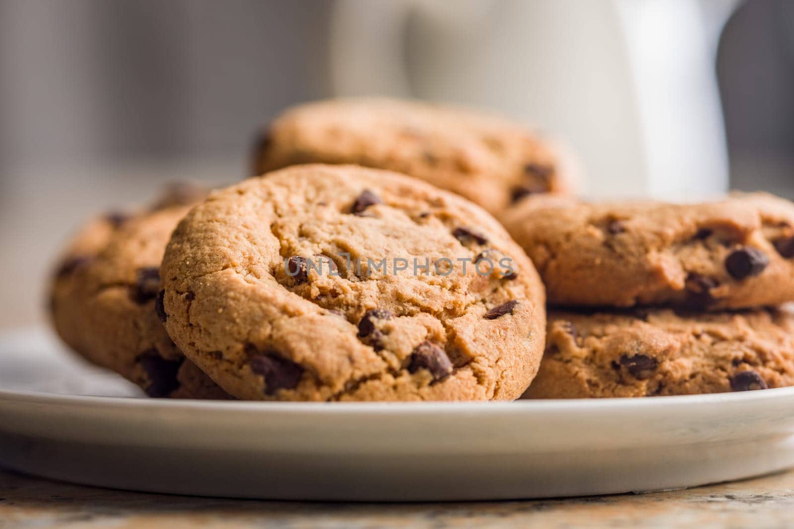 Chocolate chip cookies on plate on a kitchen table.